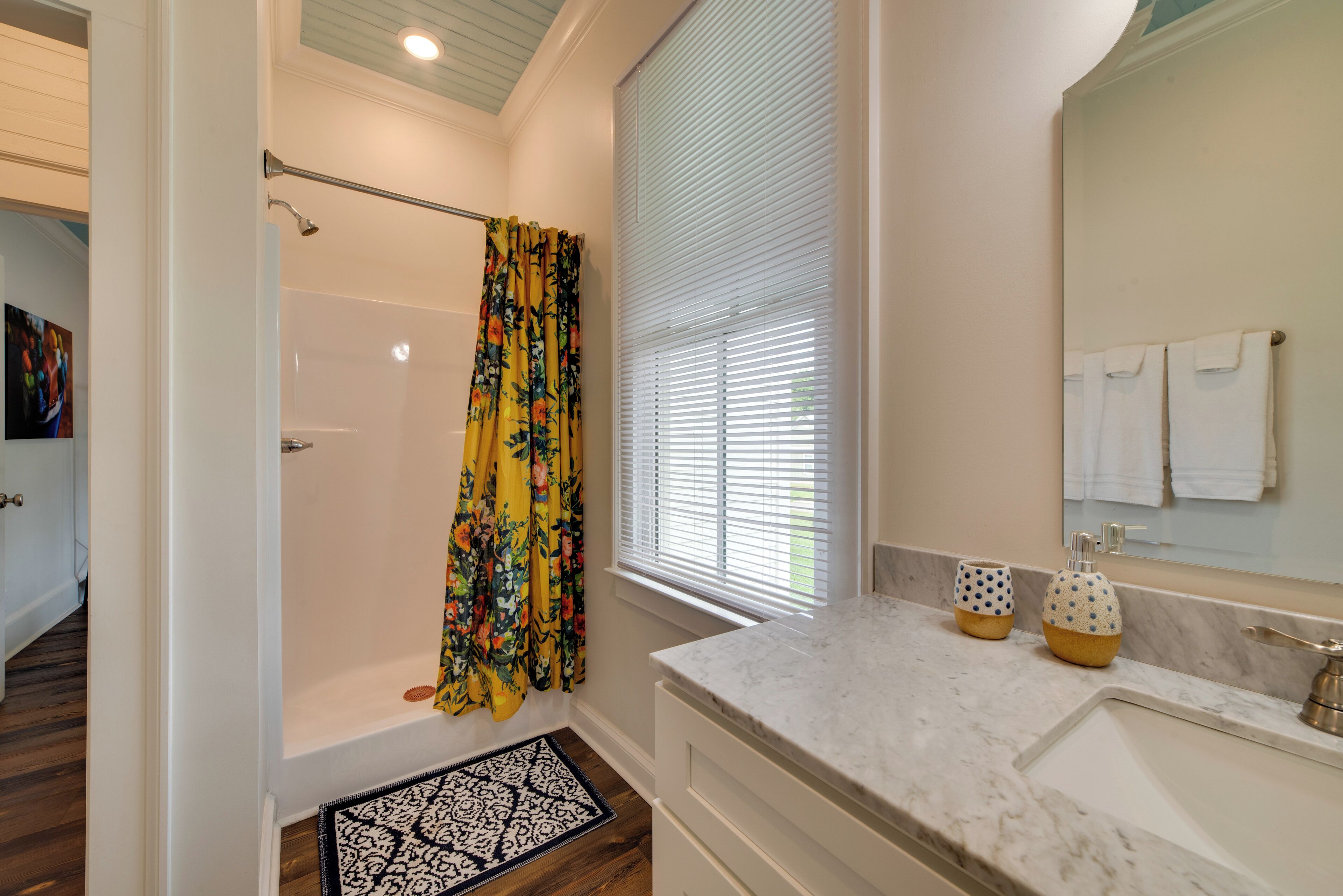 A bathroom with a shower, a bathtub, a sink, and a window with blinds.