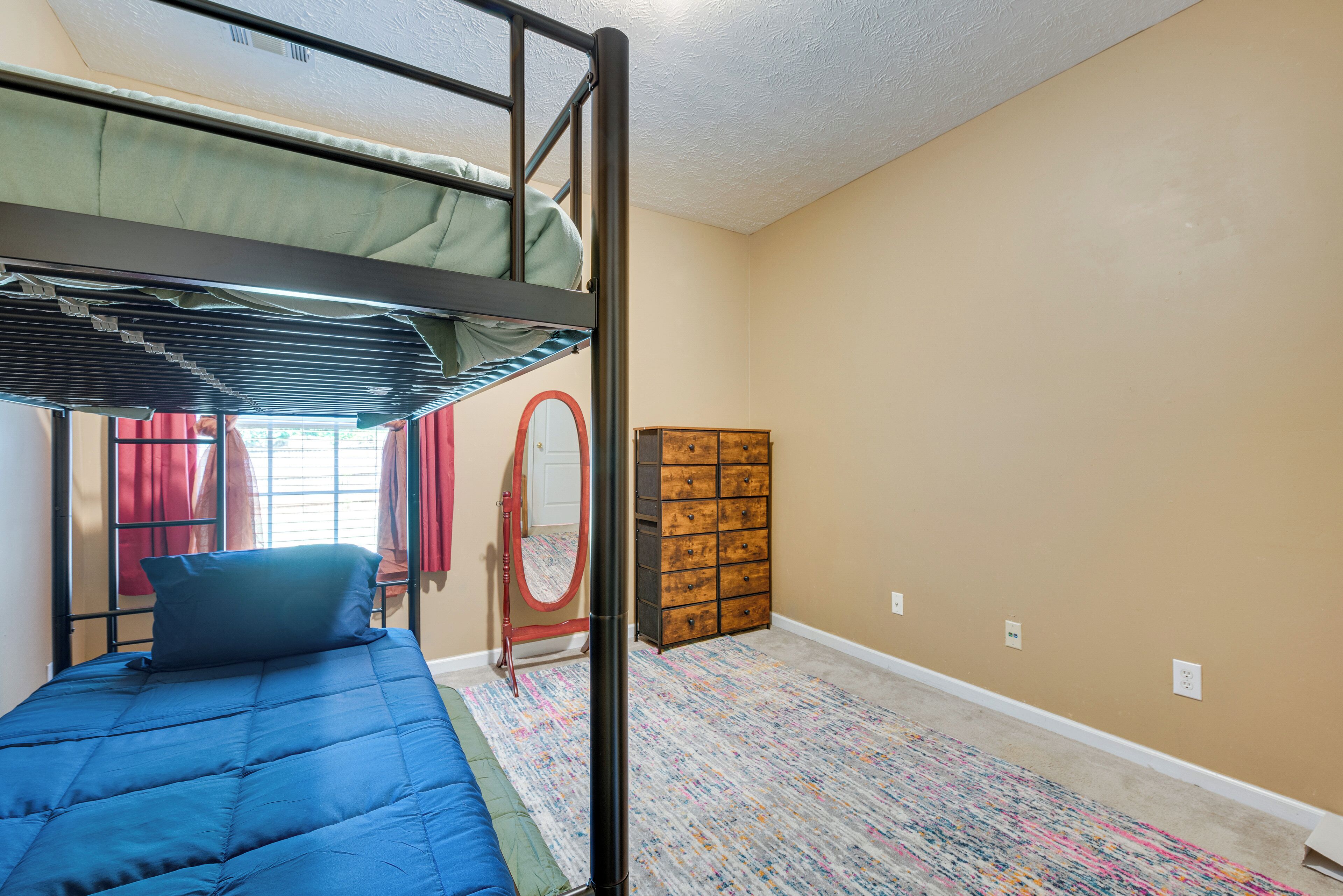 A bunk bed room with a wooden dresser and a mirror.