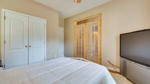 Ein Schlafzimmer mit Bett, Kleiderschrank, Fernseher und einem Fenster mit Jalousien.