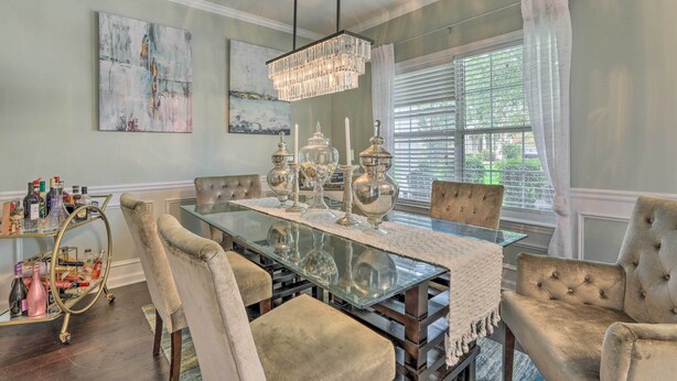 A dining room with a glass-top table, cushioned chairs, a chandelier, and artwork on the walls. - Snellville Abode < 9 Mi to Stone Mtn Park! (Snellville)