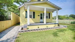 A yellow house with a porch, a wooden fence, and a paved walkway. - Charming Newport News Cottage < 1 Mi to Ocean! (Newport News)