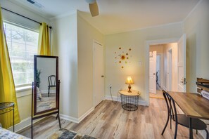 A room with a wooden floor, a mirror, a table with chairs, and a lamp.