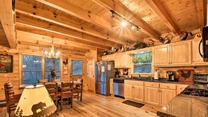 L’intérieur d’un chalet en bois comprend un coin repas, une cuisine et un lustre.