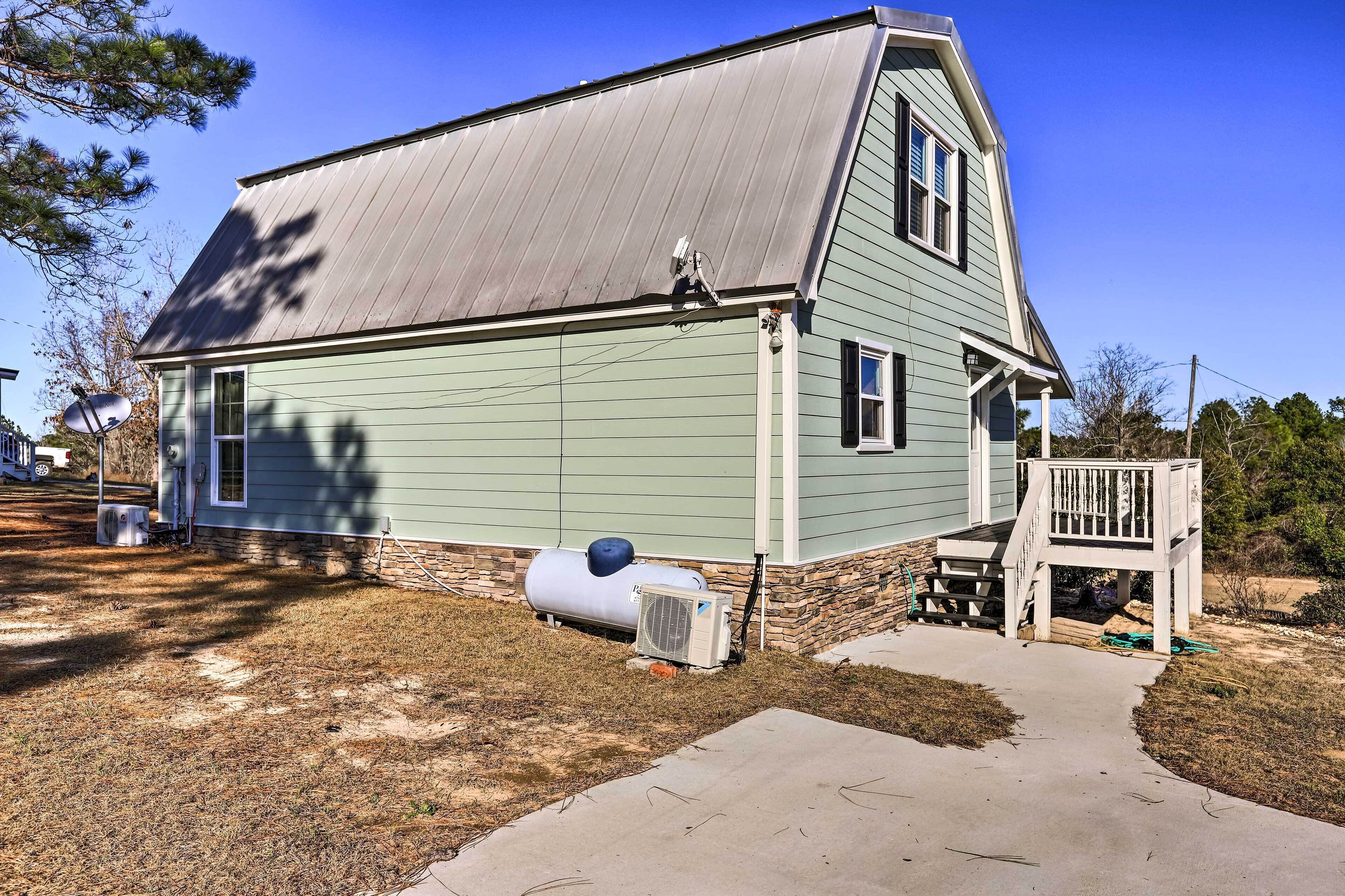 A two-story house with a metal roof, a front porch, and a satellite dish.