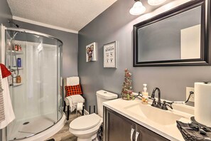A bathroom with a glass shower enclosure, a toilet, and a sink with a mirror above. - Junction City Home: Large Yard & Deck! (Junction City)