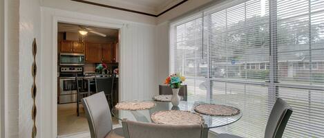 Un comedor con una mesa de vidrio, sillas y vistas a la cocina a través de un acceso.