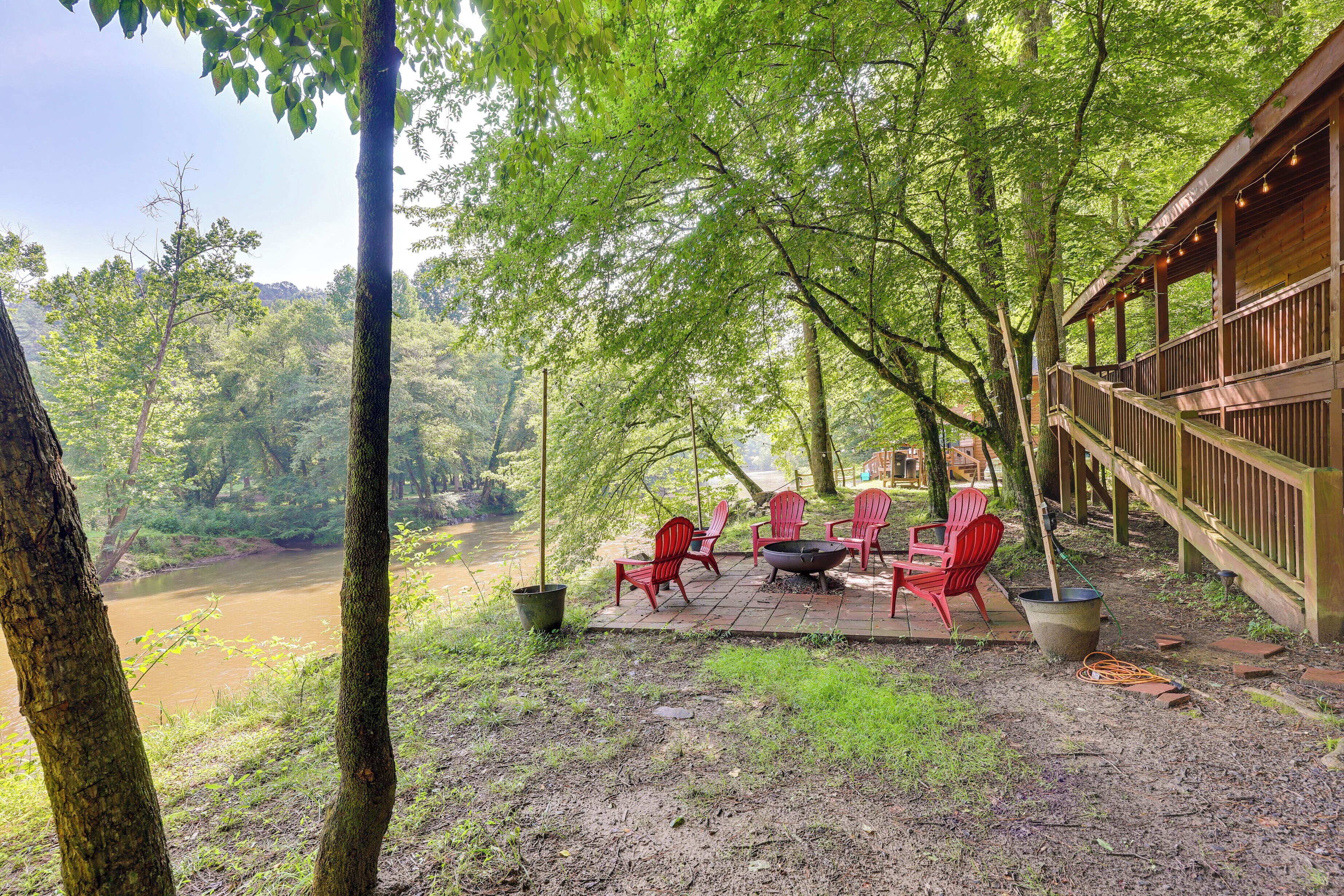 Eine Terrasse mit Sitzgelegenheit und Feuerstelle mit Blick auf einen Fluss.