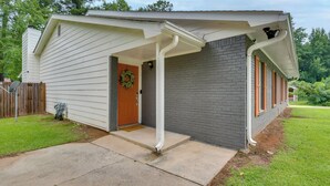 A single-story house with a covered porch, a brick exterior, and a front door with a wreath.
