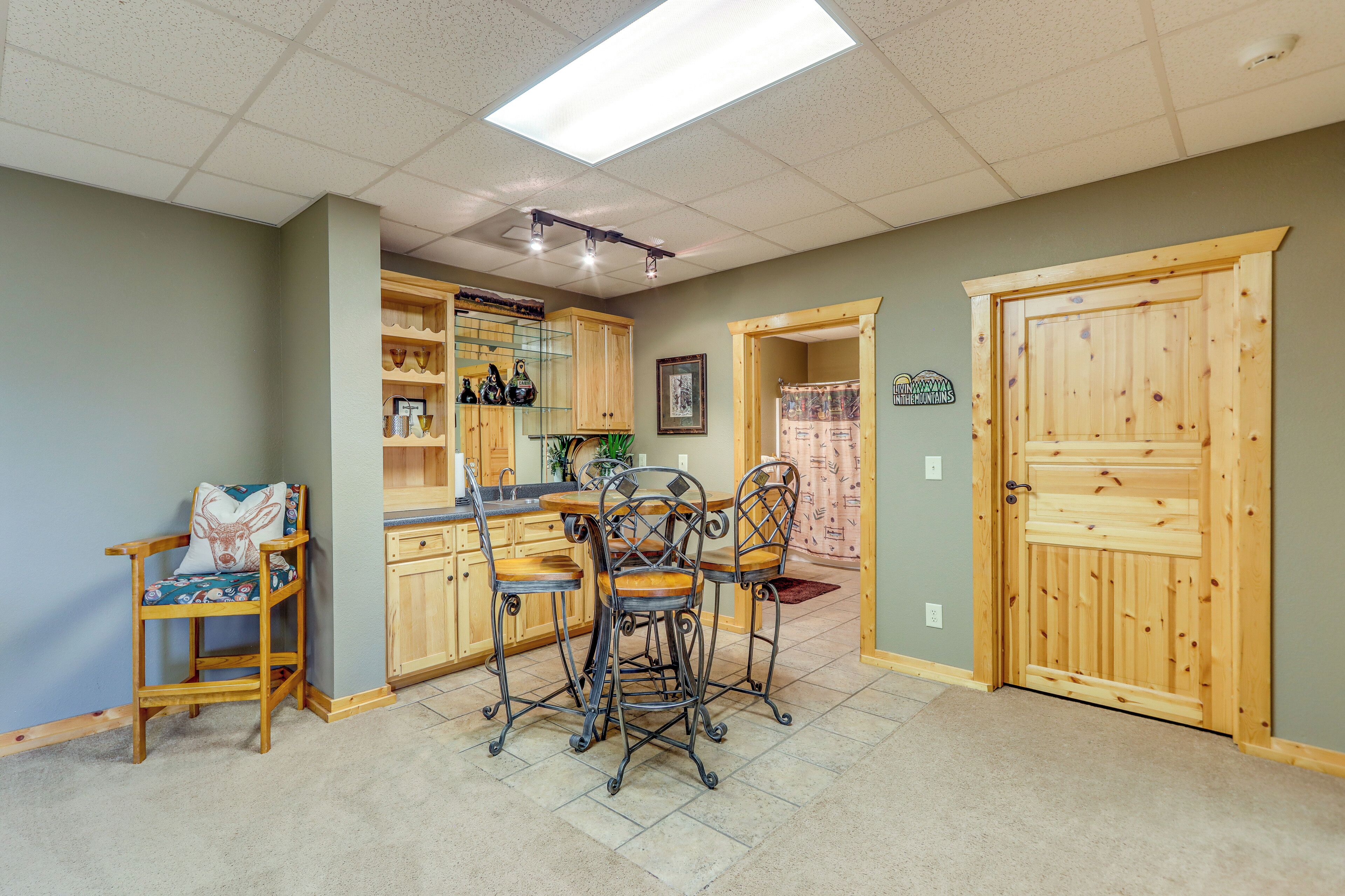 A kitchen with wooden cabinets, a dining area with metal chairs, and a wooden door.
