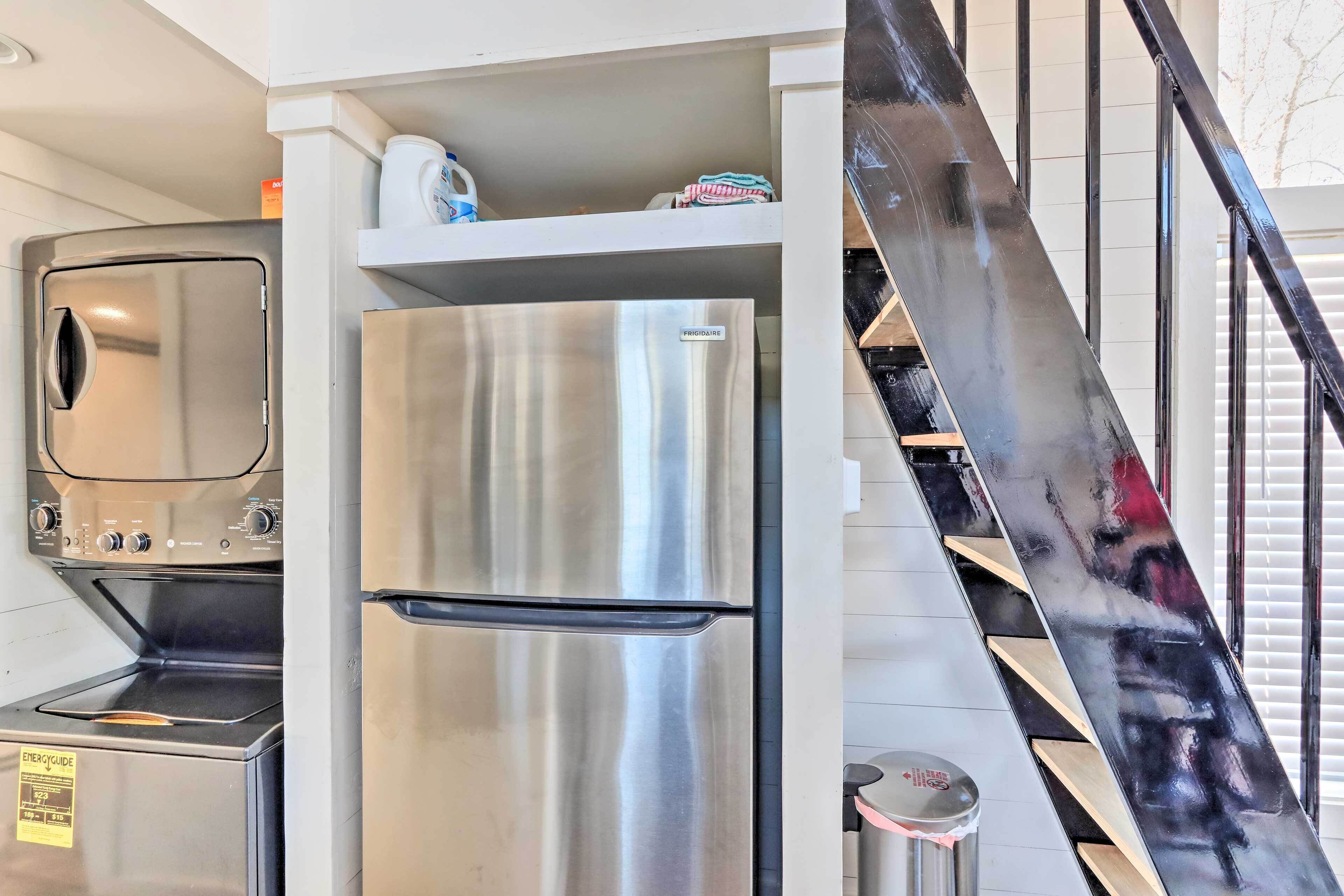 A compact kitchen with a stainless steel refrigerator, a built-in oven, and a microwave.