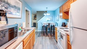 A modern kitchen with wooden cabinets, a stainless steel sink, a built-in oven, and a dining area with a table and chairs. - Horn Lake Vacation Rental ~ 14 Mi to Memphis! (Horn Lake)