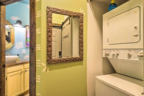 A laundry room with a large mirror, a washing machine, and a sink.