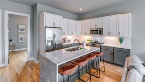 A modern kitchen with white cabinets, a marble island, and a stainless steel refrigerator. - Nashville Townhome w/ Rooftop Balcony & Game Room! (Nashville)