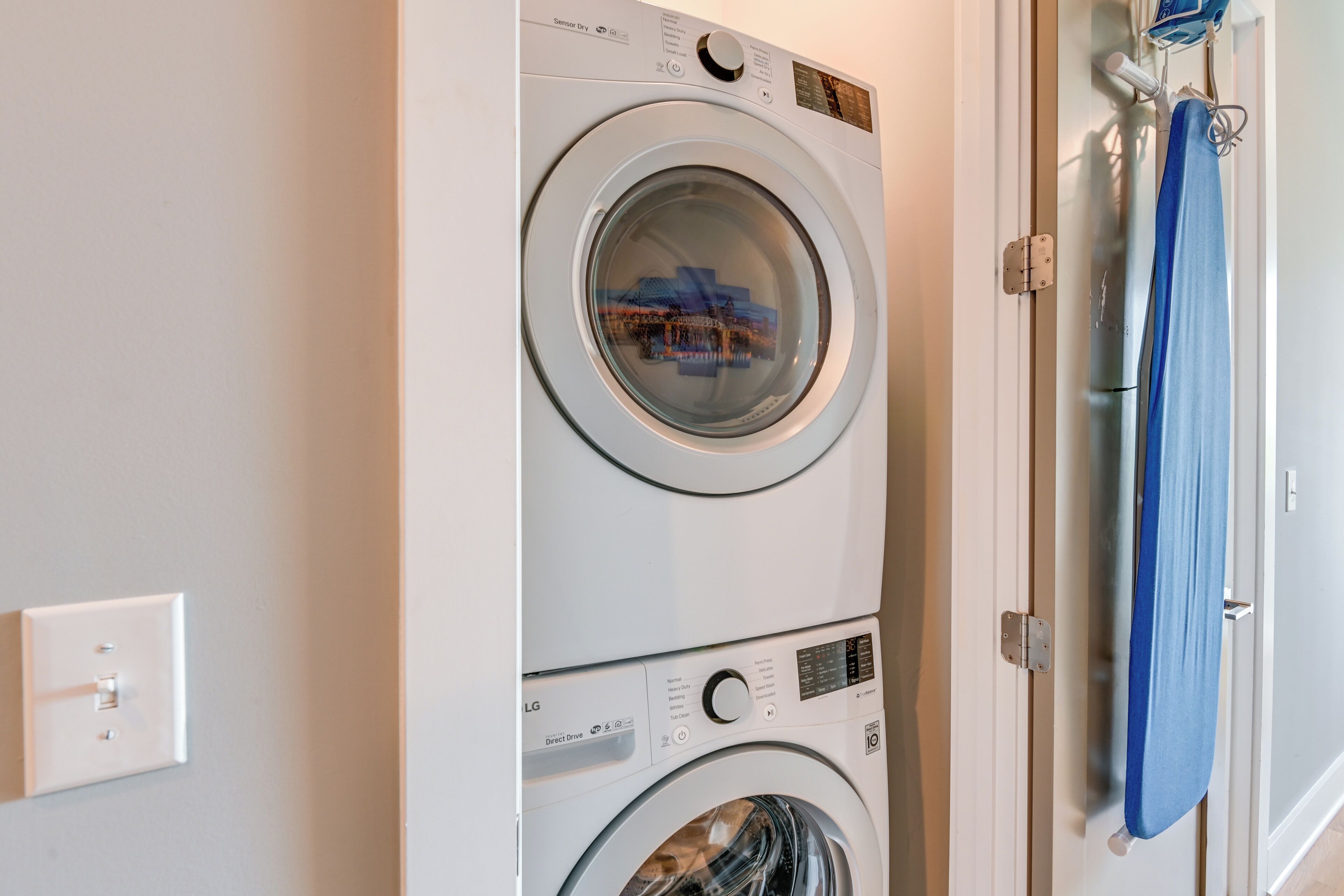 A stacked washer and dryer unit with a blue towel hanging on the wall.