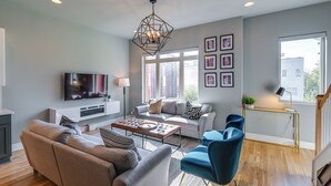 A modern living room with a sofa, armchairs, a coffee table, and a TV. - Nashville Townhome w/ Rooftop Balcony & Game Room! (Nashville)