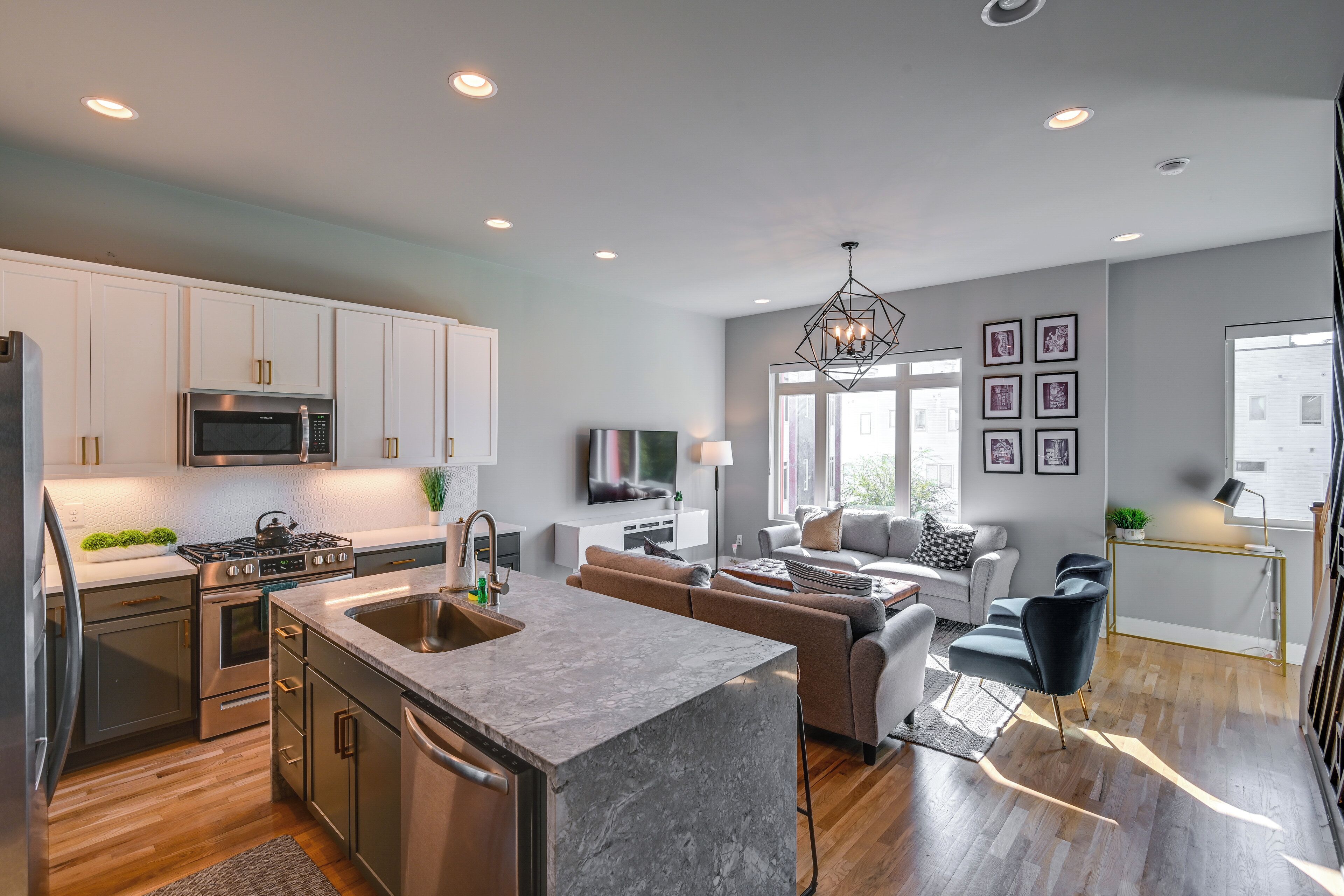 A modern kitchen with stainless steel appliances, a marble island, and a dining area with a sofa and chairs.