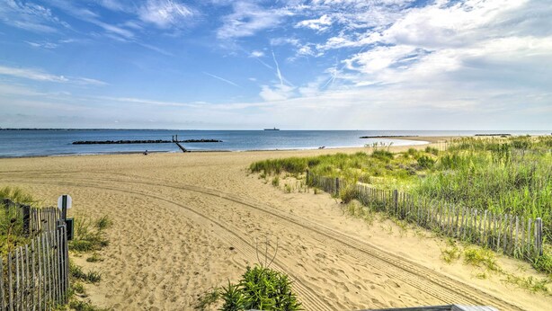 A sandy beach with a wooden fence and grassy dunes. - Inviting Norfolk Family Retreat: 1 Block to Beach! (Norfolk)