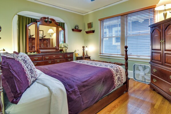 A bedroom with a large bed, wooden dresser, and a mirror. - Walk to Williams District: Home w/ Hot Tub & Patio (Portland)