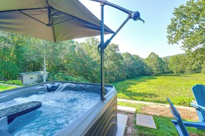 Ein Whirlpool mit Baldachin, umgeben von einem Rasen und Bäumen.