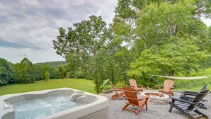 A hot tub with wooden chairs and a fire pit in a garden setting.