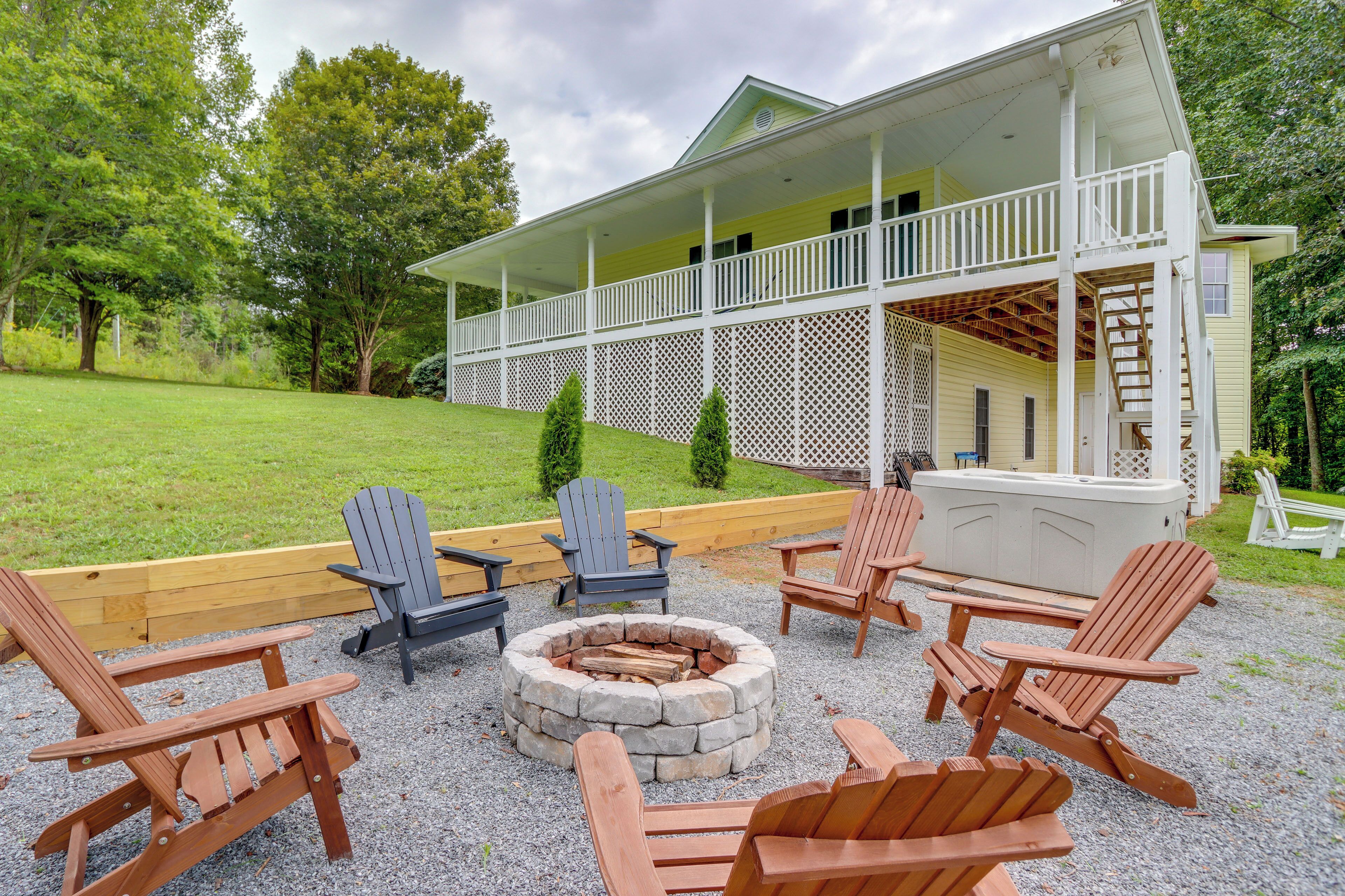A covered porch with Adirondack chairs and a fire pit, surrounded by a well-maintained lawn and trees.