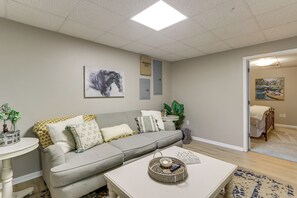 A living room with a grey sofa, a white coffee table, and a painting of a horse.