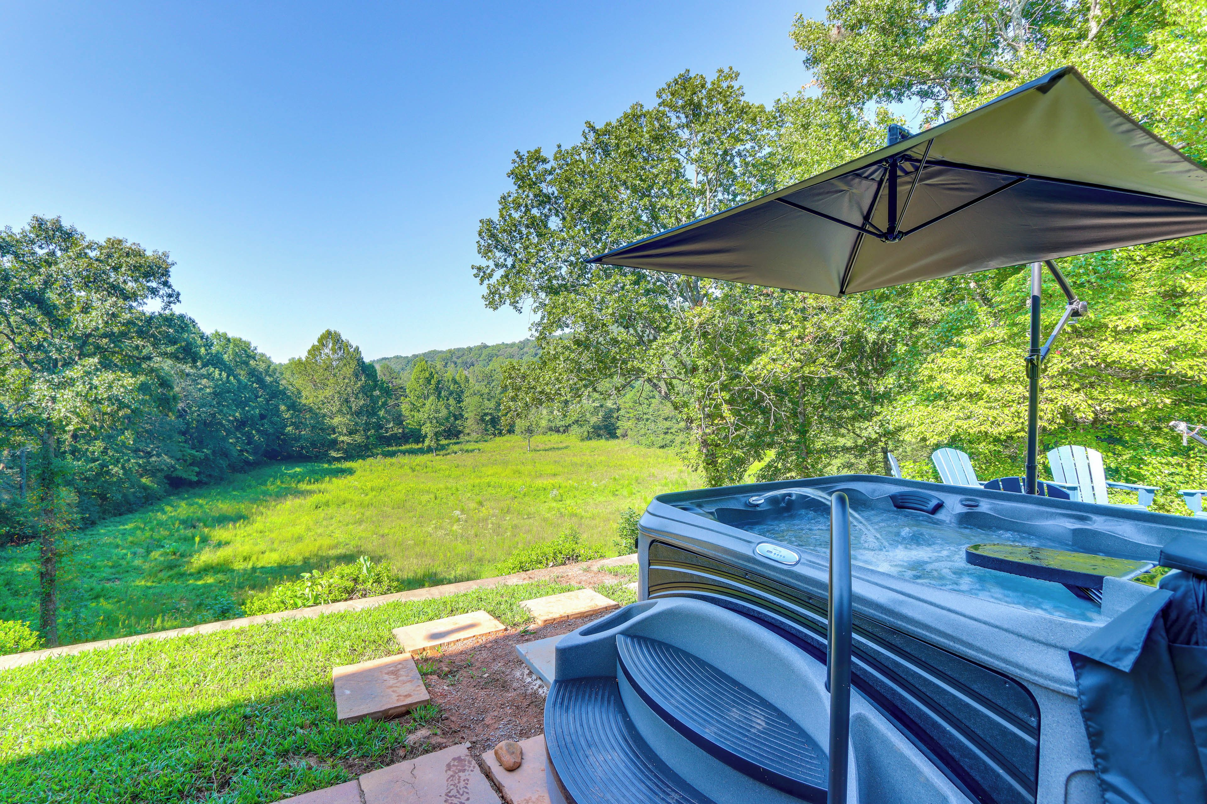 A hot tub with a canopy, surrounded by a grassy area and trees.