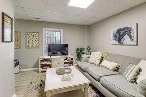 Ein Wohnzimmer mit Fernseher, Sofa, Couchtisch und gerahmten Bildern an der Wand.