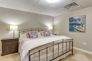 Une chambre à coucher avec un lit, des tables de chevet, un tableau et un luminaire au plafond.