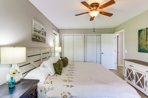 Une chambre à coucher avec un lit, un ventilateur de plafond, une table de chevet, une lampe et une commode.