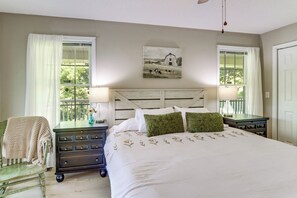 Een slaapkamer met een groot bed, twee nachtkastjes, een stoel en een schilderij aan de muur.