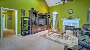 A living room with a fireplace, a television, and a leather sofa. - Spacious Acworth Home w/ Deck ~ 1 Mi to Lake (Acworth)
