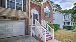 A two-story house with a front garage, a white staircase with a lattice balustrade, and a brick facade. - Spacious Acworth Home w/ Deck ~ 1 Mi to Lake (Acworth)