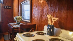 A kitchen with a white stove, wooden walls, a dining table with chairs, and a vase with flowers. - 8 Mi to Broadway: Wfh-friendly Nashville Duplex! (Nashville)