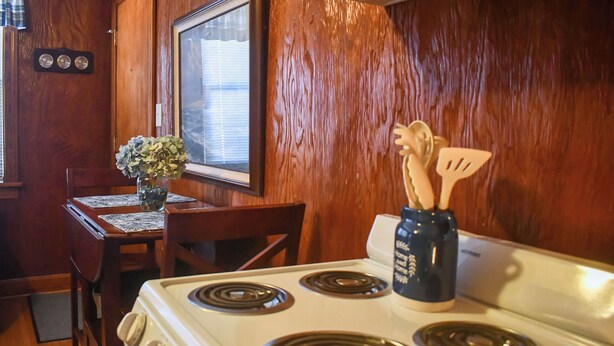A kitchen with a white stove, wooden walls, a dining table with chairs, and a vase with flowers. - 8 Mi to Broadway: Wfh-friendly Nashville Duplex! (Nashville)