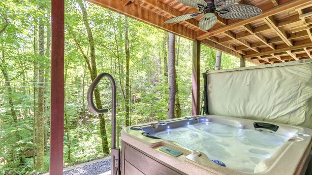Ein Whirlpool mit Bedienfeld, umgeben von einer Holzterrasse und Blick ins Waldgebiet.