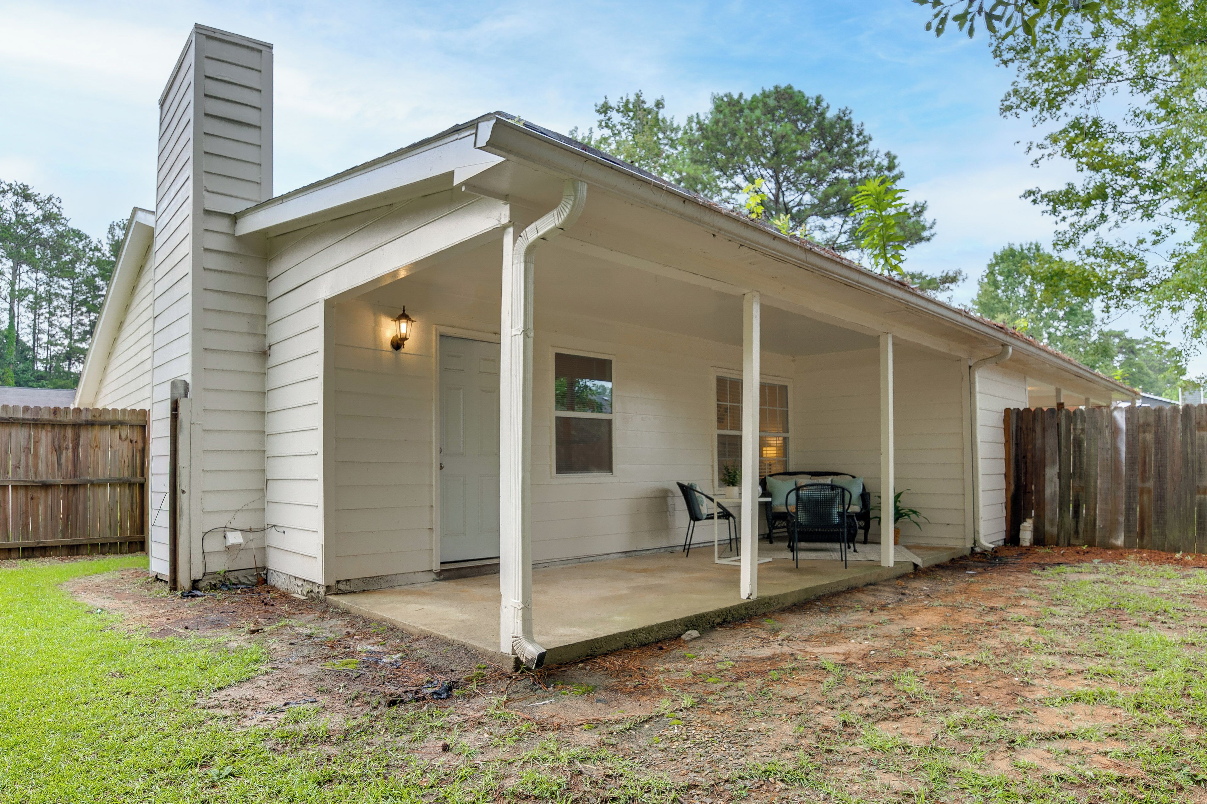 A covered patio with a concrete floor, a wooden fence, and a single window.