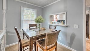 A dining area with a marble table, leather chairs, a vase with flowers, and a kitchen visible through a window. - Charming Marietta Home ~ 7 Mi to Downtown! (Marietta)