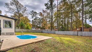A backyard with a swimming pool, a wooden fence, and trees with autumn foliage. - Charming Marietta Home ~ 7 Mi to Downtown! (Marietta)
