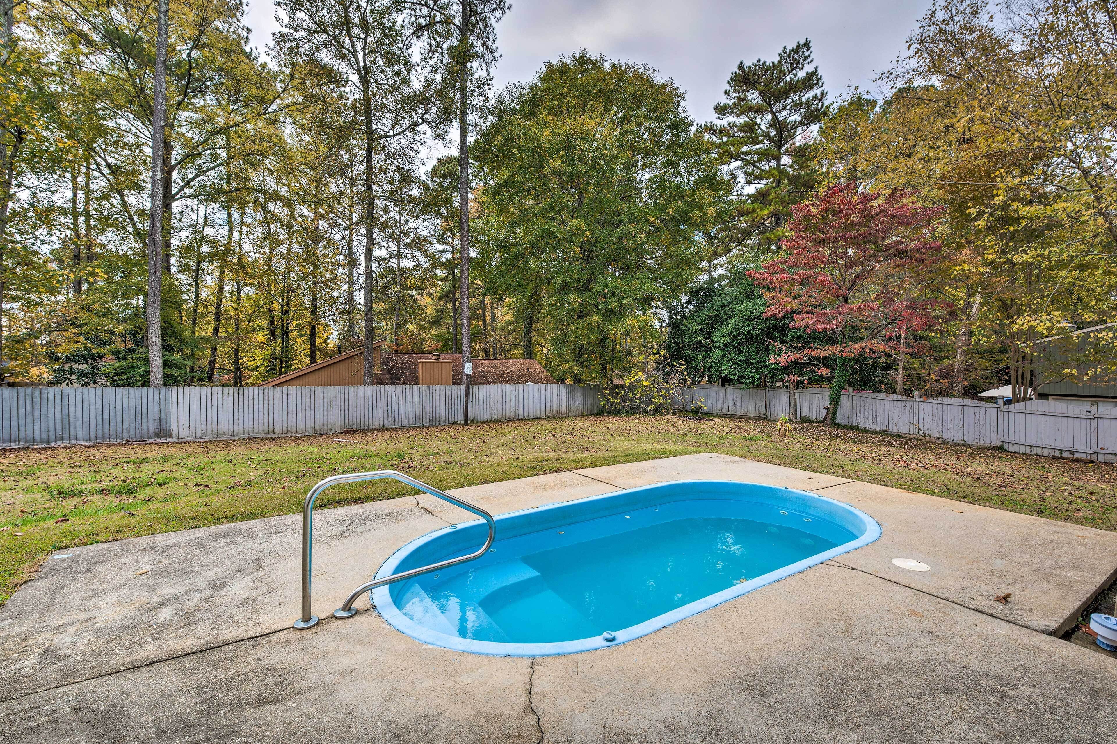 A backyard with a swimming pool, surrounded by trees and a wooden fence.