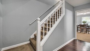 A staircase with white balusters and a beige carpeted landing. - Charming Marietta Home ~ 7 Mi to Downtown! (Marietta)
