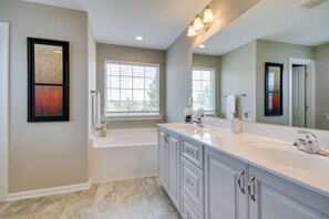 A modern bathroom with a large bathtub, a double sink vanity, and a large mirror.