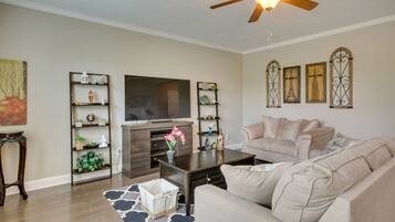 A living room with a beige sofa, a coffee table, a TV, and decorative shelves.