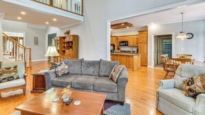 Un salon spacieux avec un canapé gris, une table basse en bois et un escalier menant à l’étage supérieur.