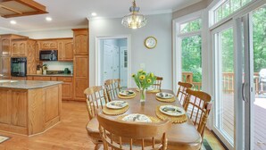 Une cuisine spacieuse dotée de meubles en bois, d’un îlot central et d’un coin repas avec une table dressée pour six personnes.