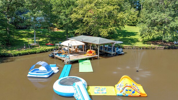 A water park with inflatable water slides and a covered pavilion. - Waterfront Sparta Home w/ Game Room & Fire Pit! (Eatonton)