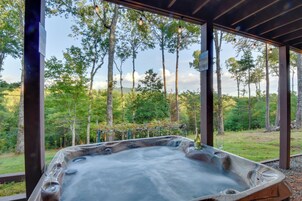 Un jacuzzi con una copa y una botella de vino, rodeado por una terraza de madera y vistas a un bosque.