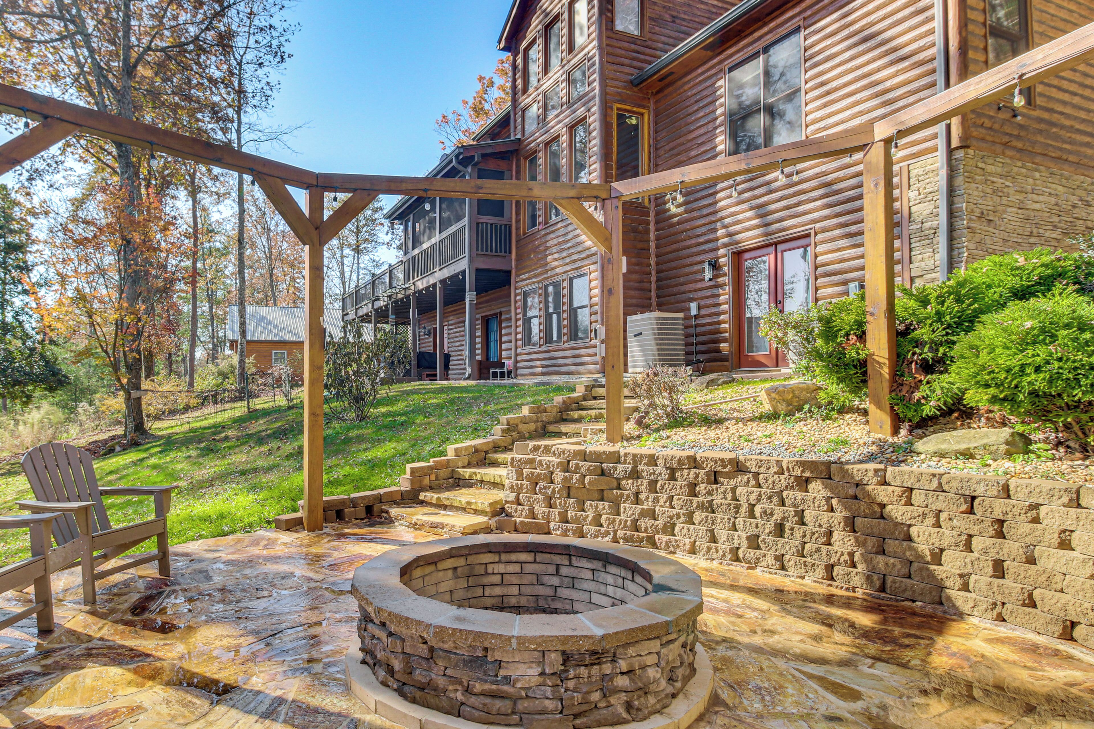 A wooden cabin with a stone fire pit, outdoor seating, and a stone retaining wall.