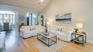 Ein geräumiges Wohnzimmer mit zwei weißen Sofas, einem Couchtisch und einem Bild an der Wand.