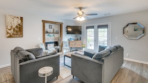 Ein Wohnzimmer mit zwei grauen Sofas, einem Couchtisch, einem Fernseher und einem Deckenventilator.